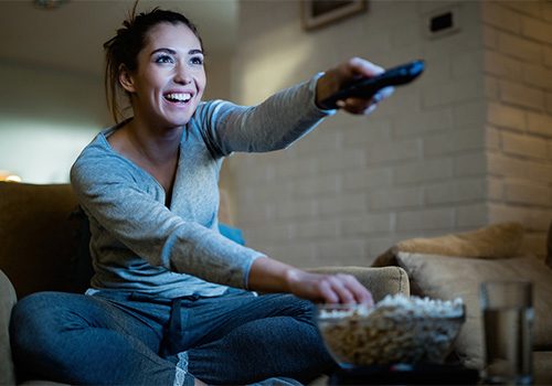 Person holding remote, eating popcorn and watching a movie