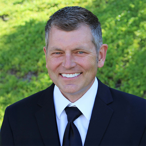 Portrait of Mark Hendrickson in black suit and tie