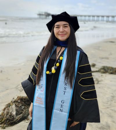 Woman posing on the beach in her graduation regalia